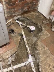 Technician checking for pipe leaks under flooring